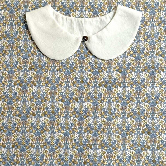 A white collar is displayed against a patterned fabric background.