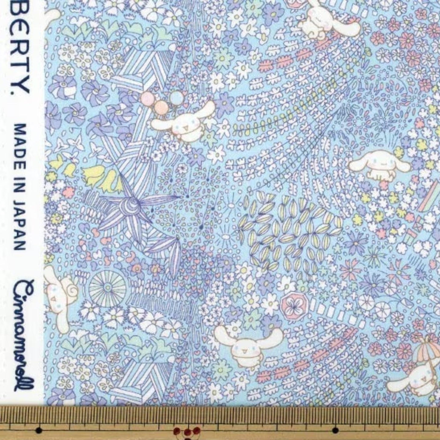 The image is a fabric with a colorful, whimsical pattern featuring various elements such as flowers, leaves, and small animals. The pattern is detailed and intricate, with a variety of colors and shapes creating a visually appealing and lively design.