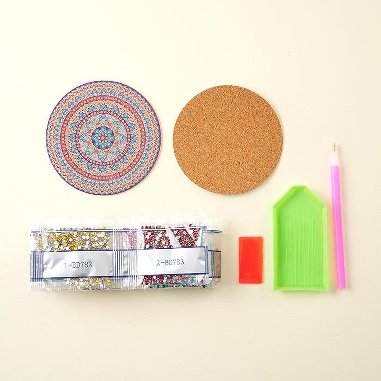 various craft supplies, including a cork coaster, a pen, a magnifying glass, a package of glitter, and a diamond tool.
