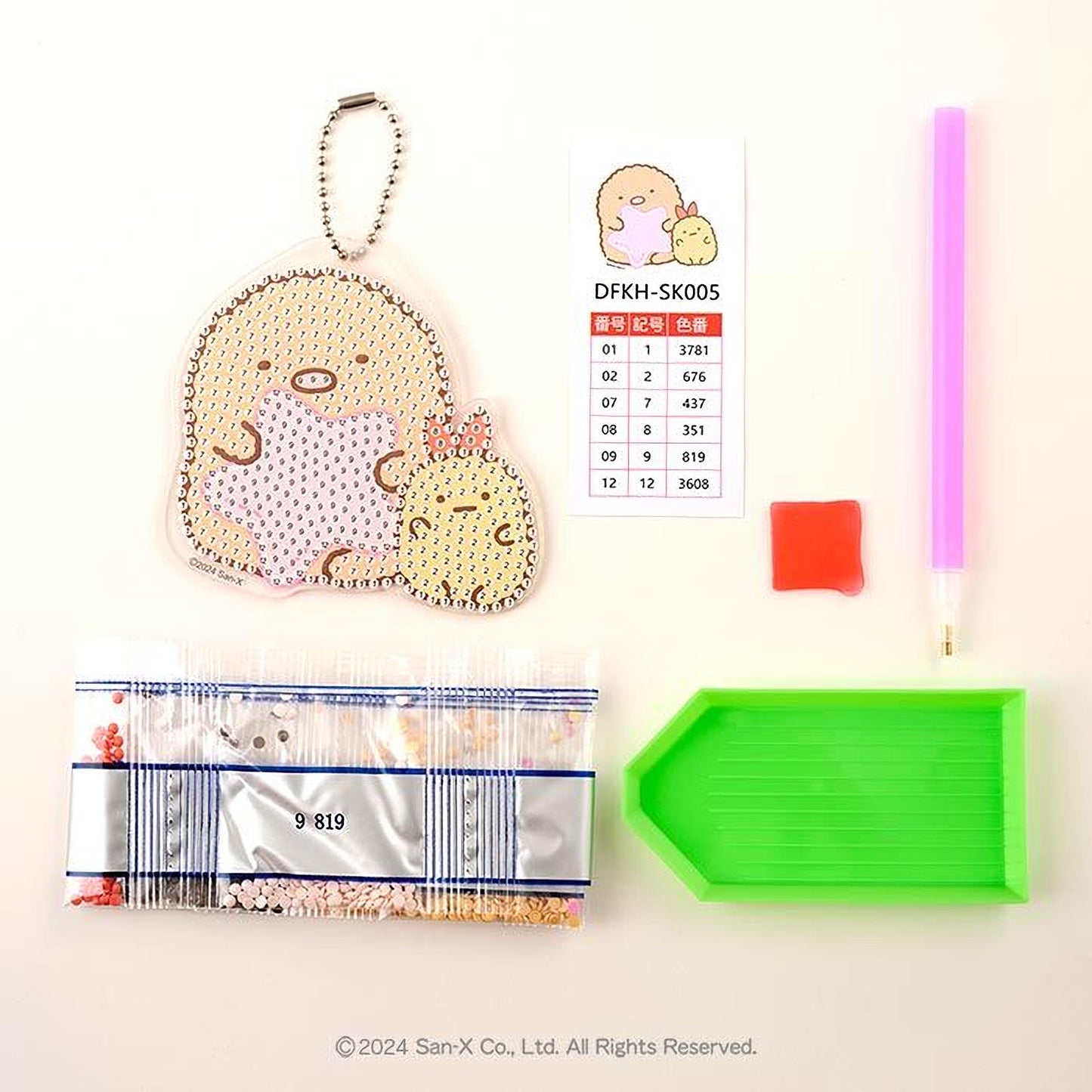 various items related to a craft or hobby, including a keychain, a price list, a pen, a green plastic tray, and a diamond grinder.
