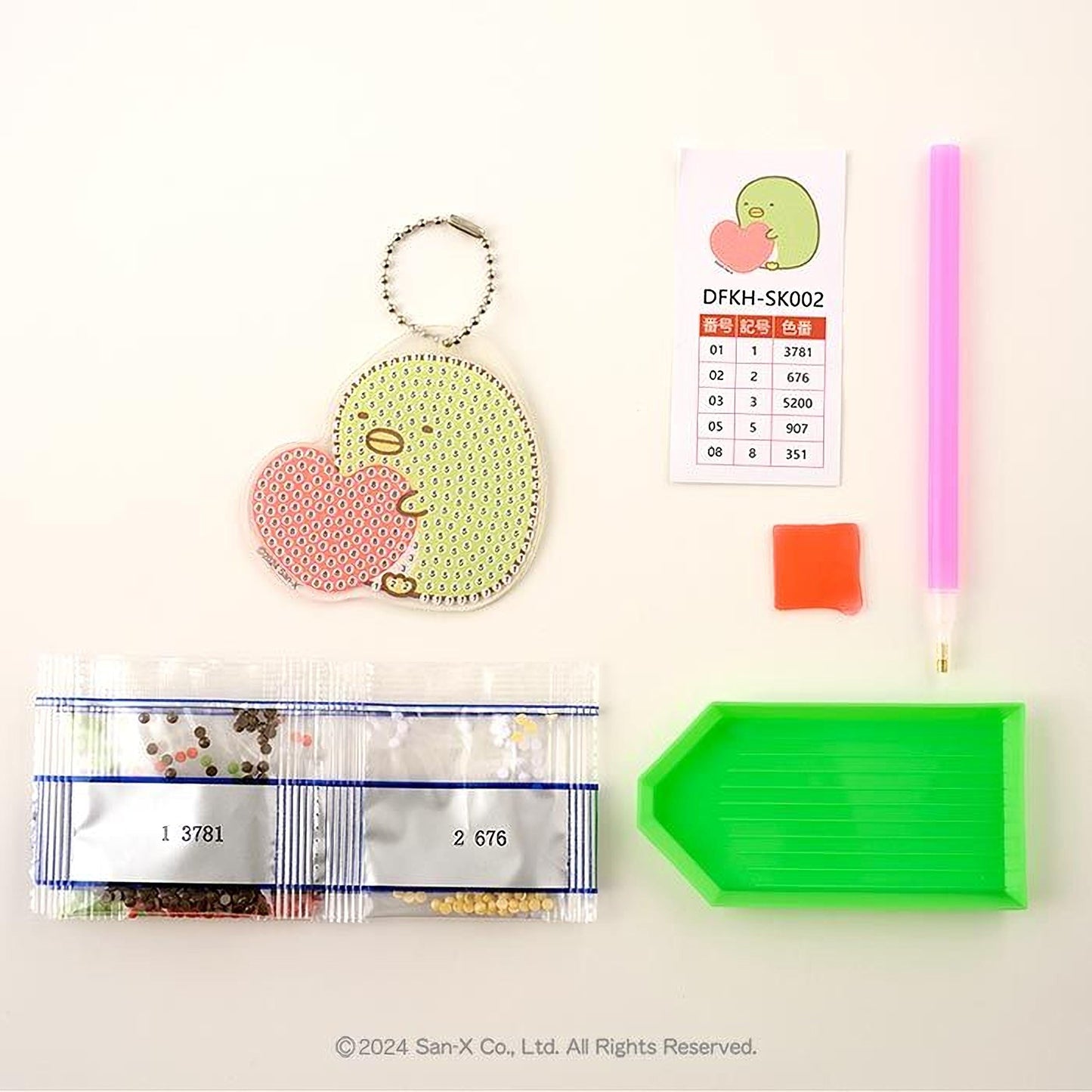 various items related to a craft or hobby, including a keychain, a price list, a pen, a green plastic tray, and a package of beads.