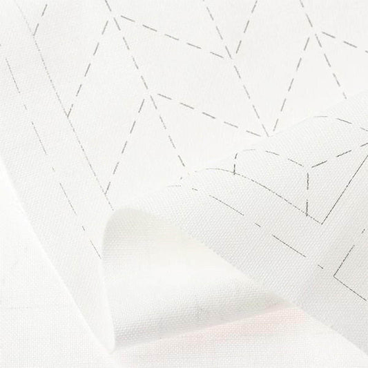 a close-up view of a white fabric with a geometric pattern, featuring a repeating diamond shape and a zigzag pattern.