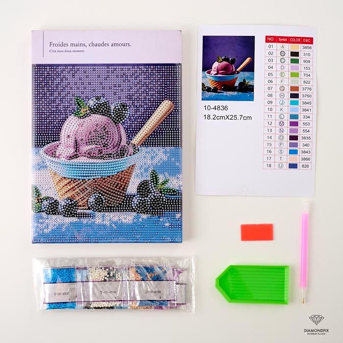 a box of diamond-encrusted paper, a kit for creating a diamond-encrusted paper craft, and various craft supplies such as a pen, a green plastic tool, and a red tool.