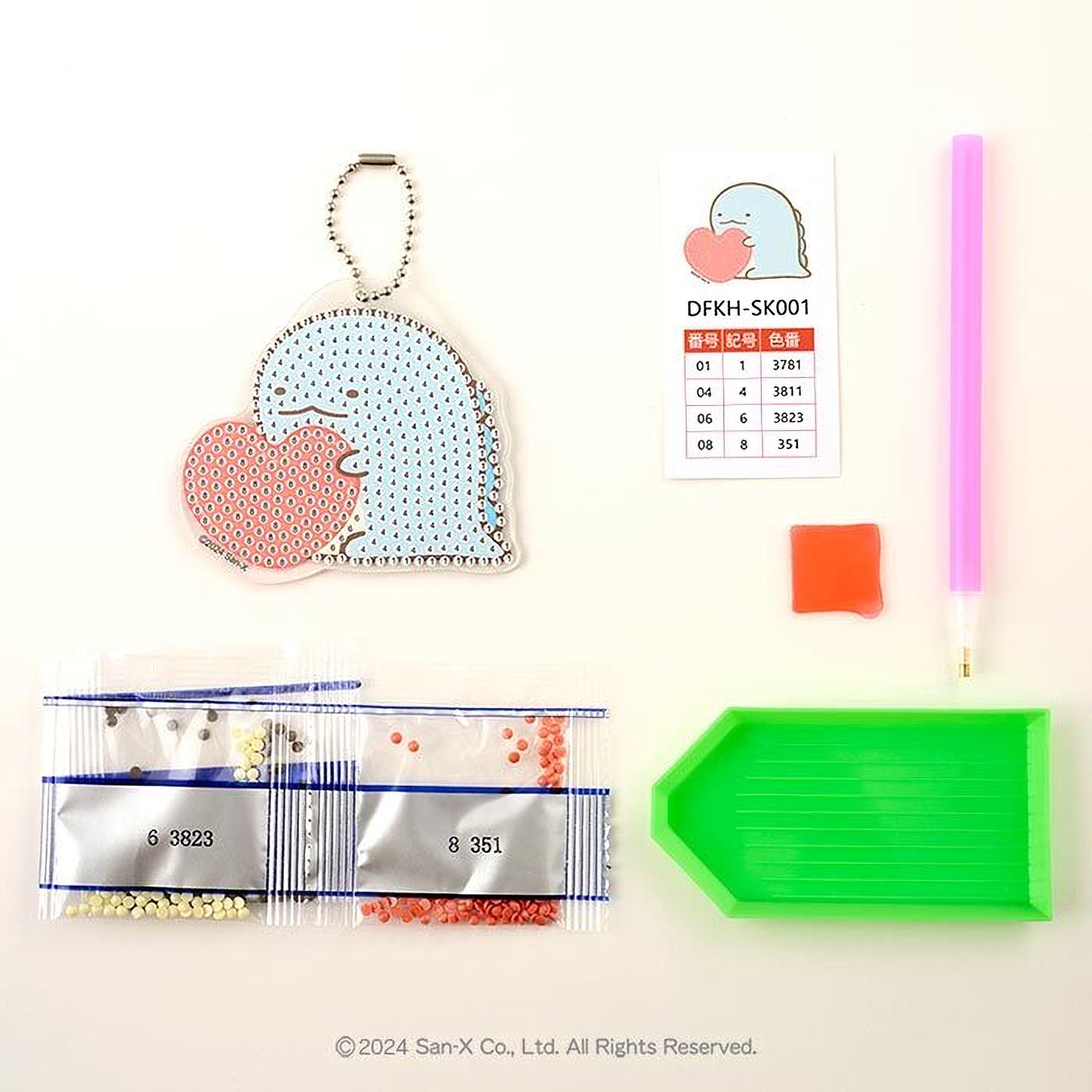 various craft supplies, including a keychain, a price list, a pen, a bag of beads, and a diamond tool.