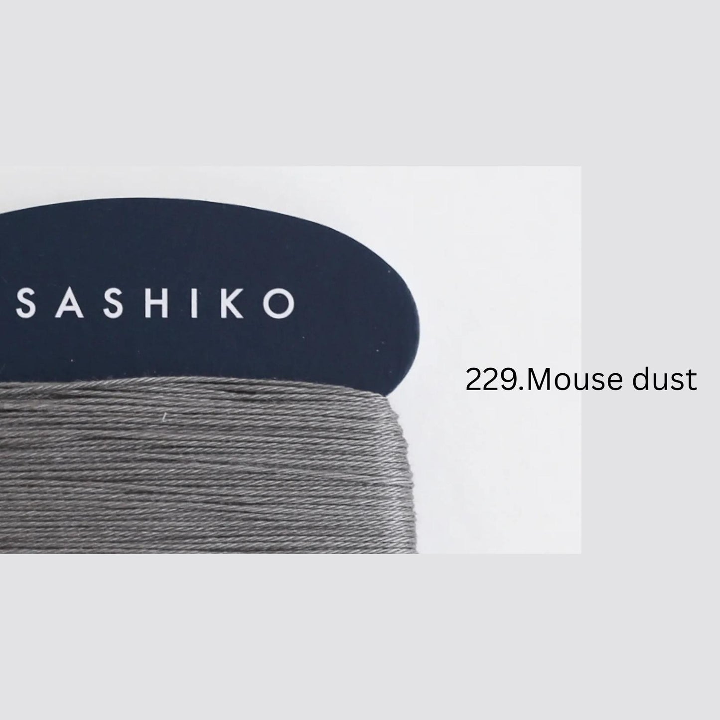 a close-up view of a dark blue object with the word "SASHIKO" written on it, along with a pile of gray yarn.