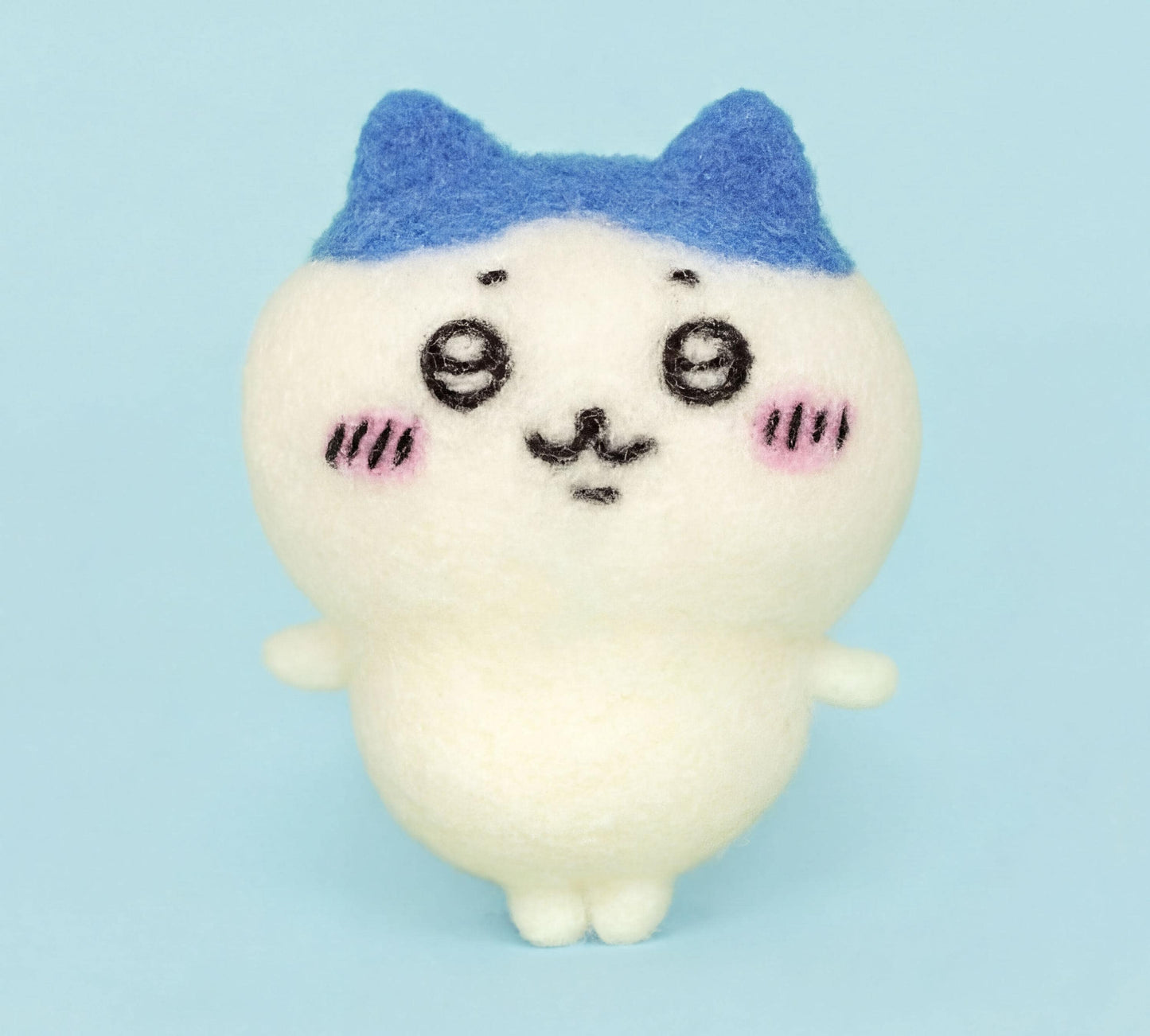 A white plush toy with blue ears and a face, featuring a small smile and pink cheeks, is the main subject of the image.
