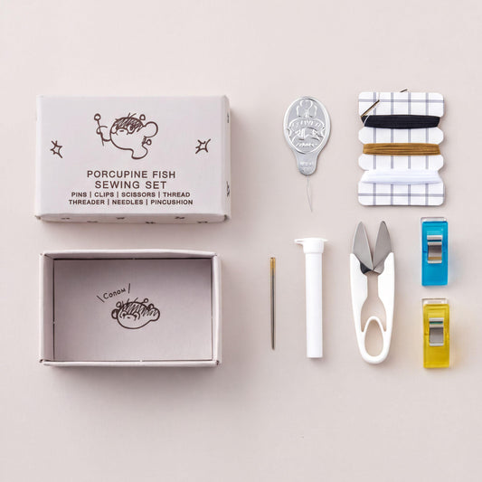 Porcupine Fish Sewing Set, Needles, Scissors, thread, threader, needles, pincushion, pin cushion, thimble, and scissors are arranged on a light background.