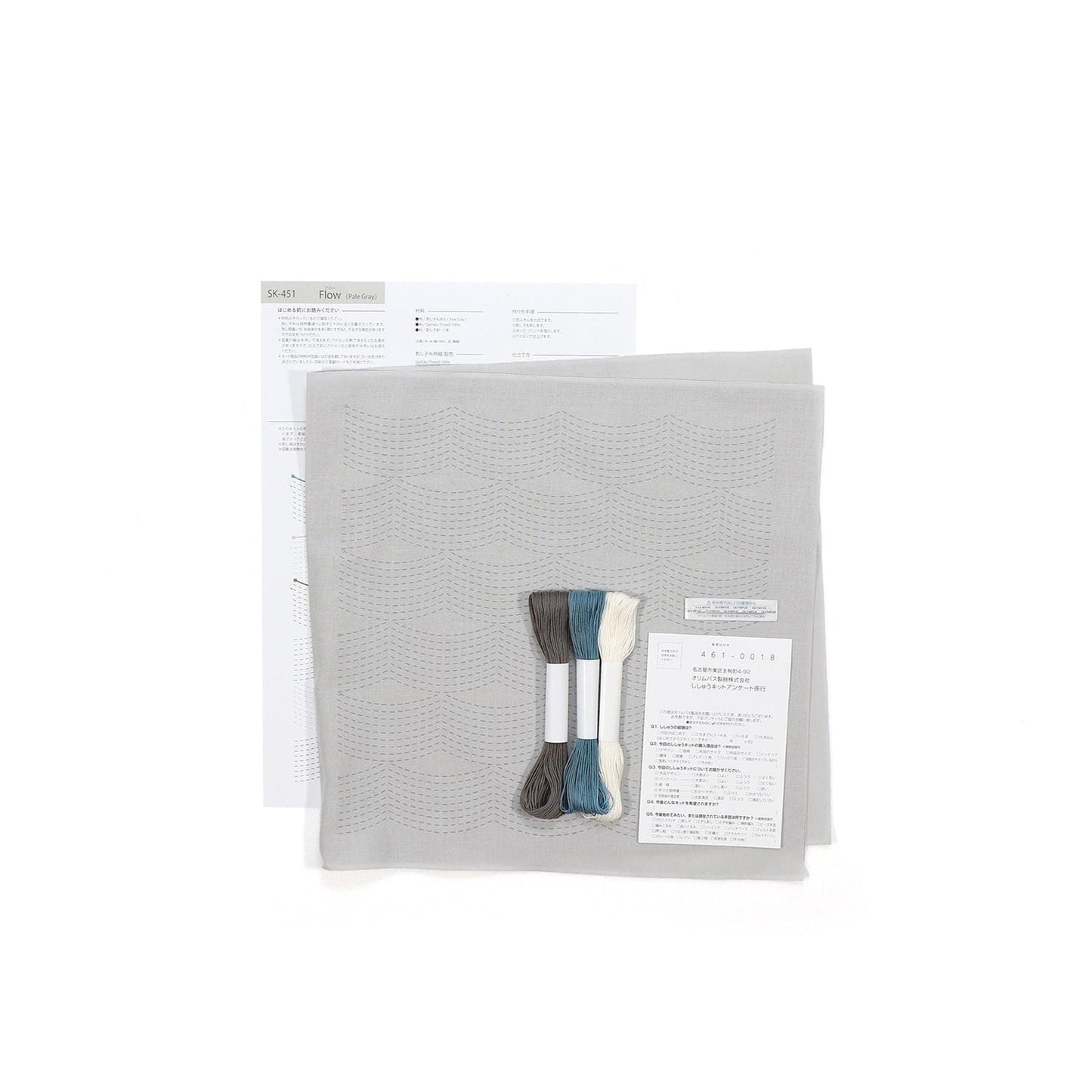 a gray fabric with a pattern, along with some thread and a piece of paper with instructions or information about the fabric.