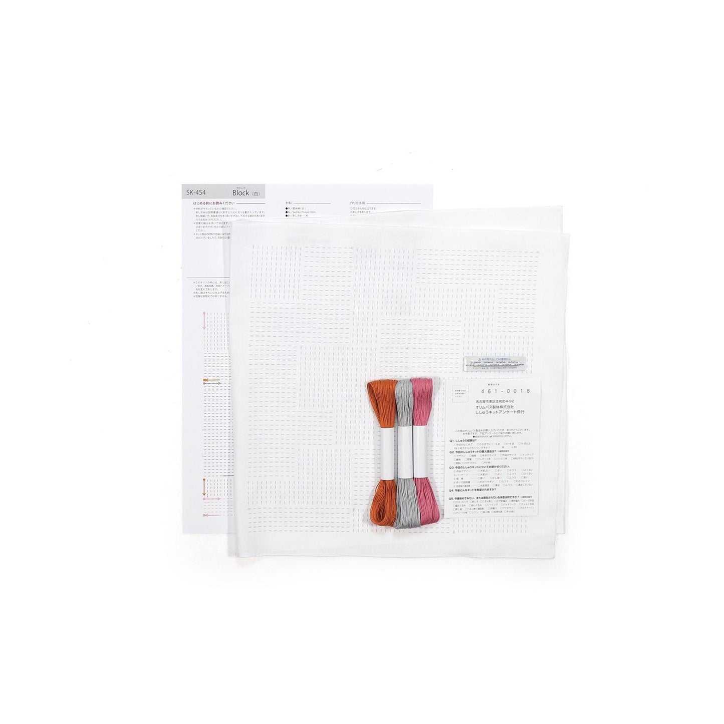 a cross-stitch kit with a white grid pattern, a pair of embroidery floss, and instructions or a diagram.
