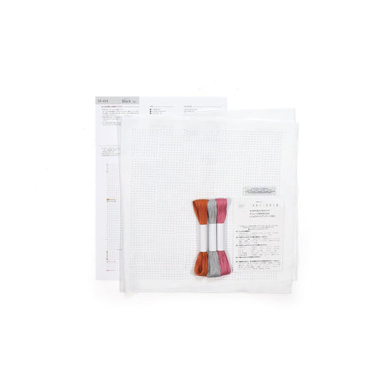a cross-stitch kit with a white grid pattern, a pair of embroidery floss, and instructions or a diagram.