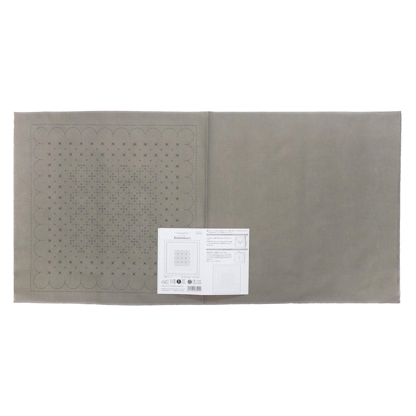 a gray fabric with a pattern of small circles or dots on it, and there is a white paper with text and diagrams attached to it.