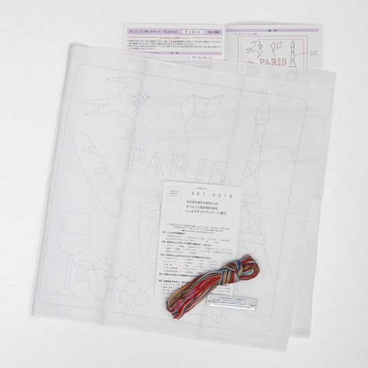 a paper with a drawing of Paris, a piece of paper with instructions, and a spool of thread with a colorful string.