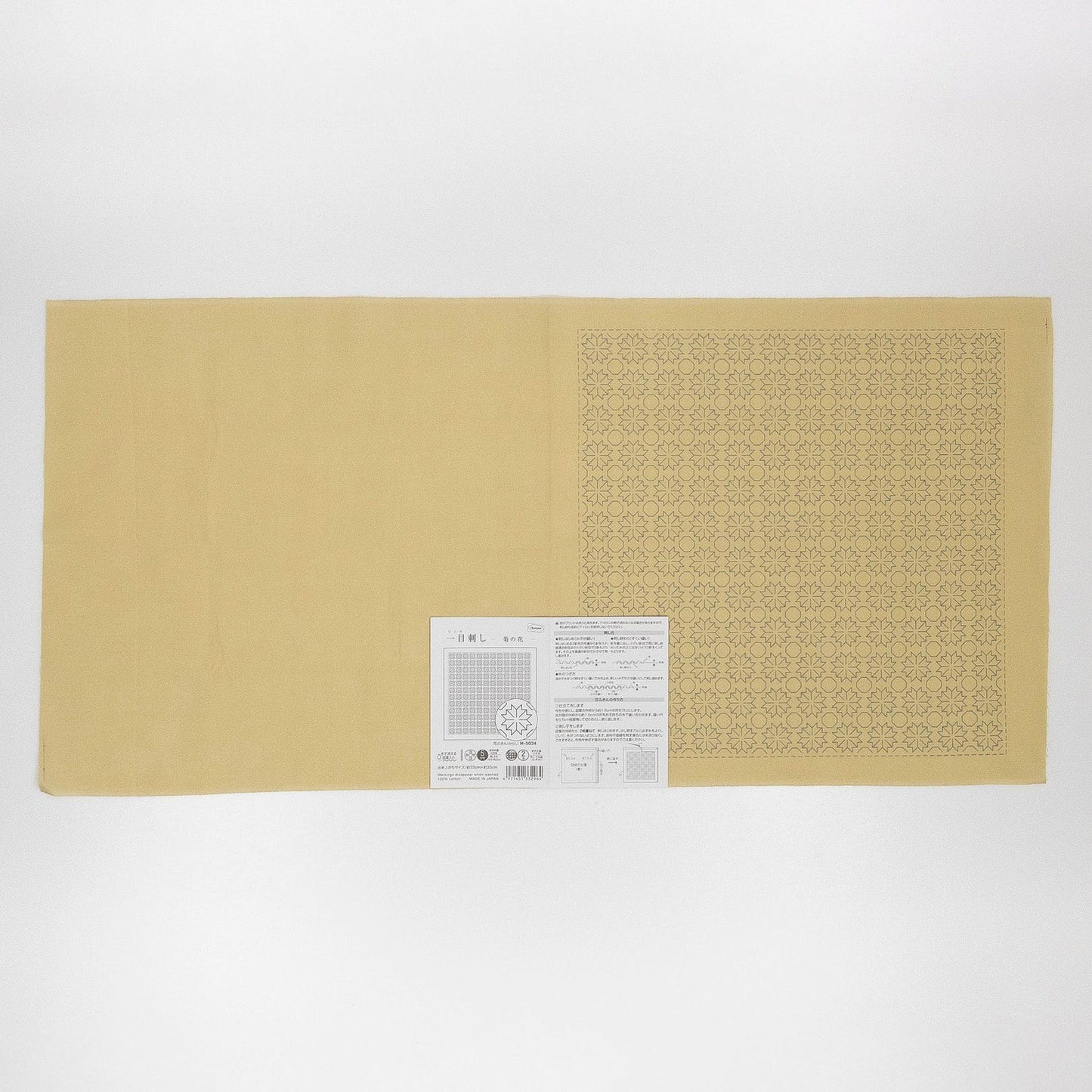 The image is a single, long, beige-colored object with a grid pattern on it. There is a small, white label with text and a barcode attached to the object.