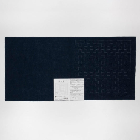The image is a dark blue fabric with a white pattern on it, and there is a small white label with text attached to the bottom right corner of the fabric.