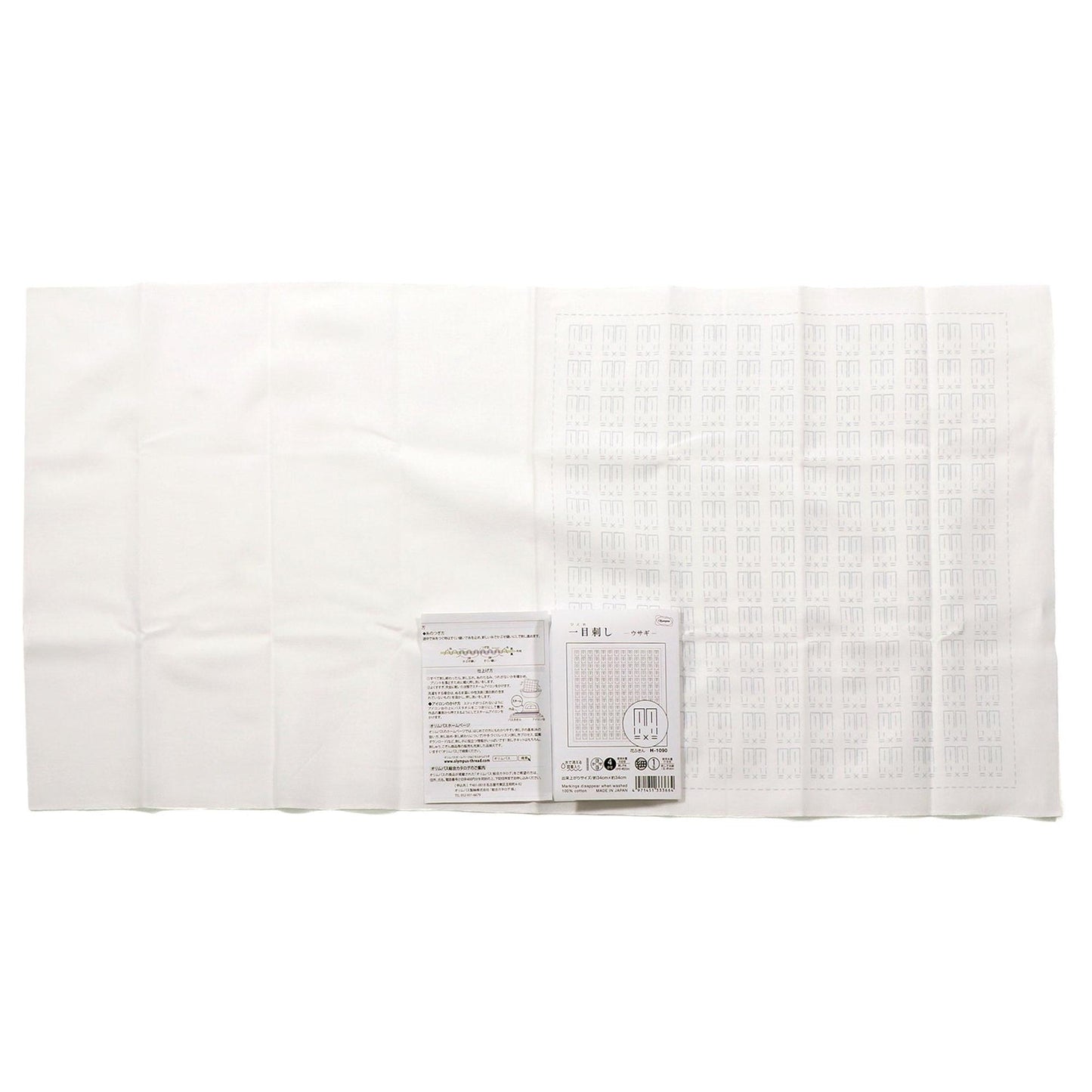 a white cloth with a grid pattern, and there is a small white paper with text and a barcode next to it.