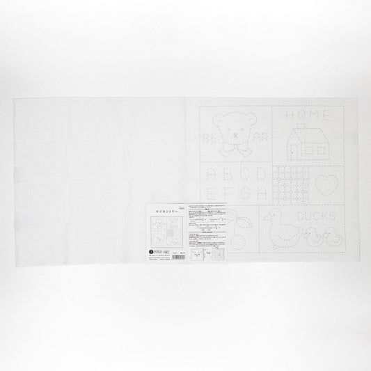 The image is a white sheet of paper with various drawings and text, including a teddy bear, a house, and some other abstract shapes and symbols.