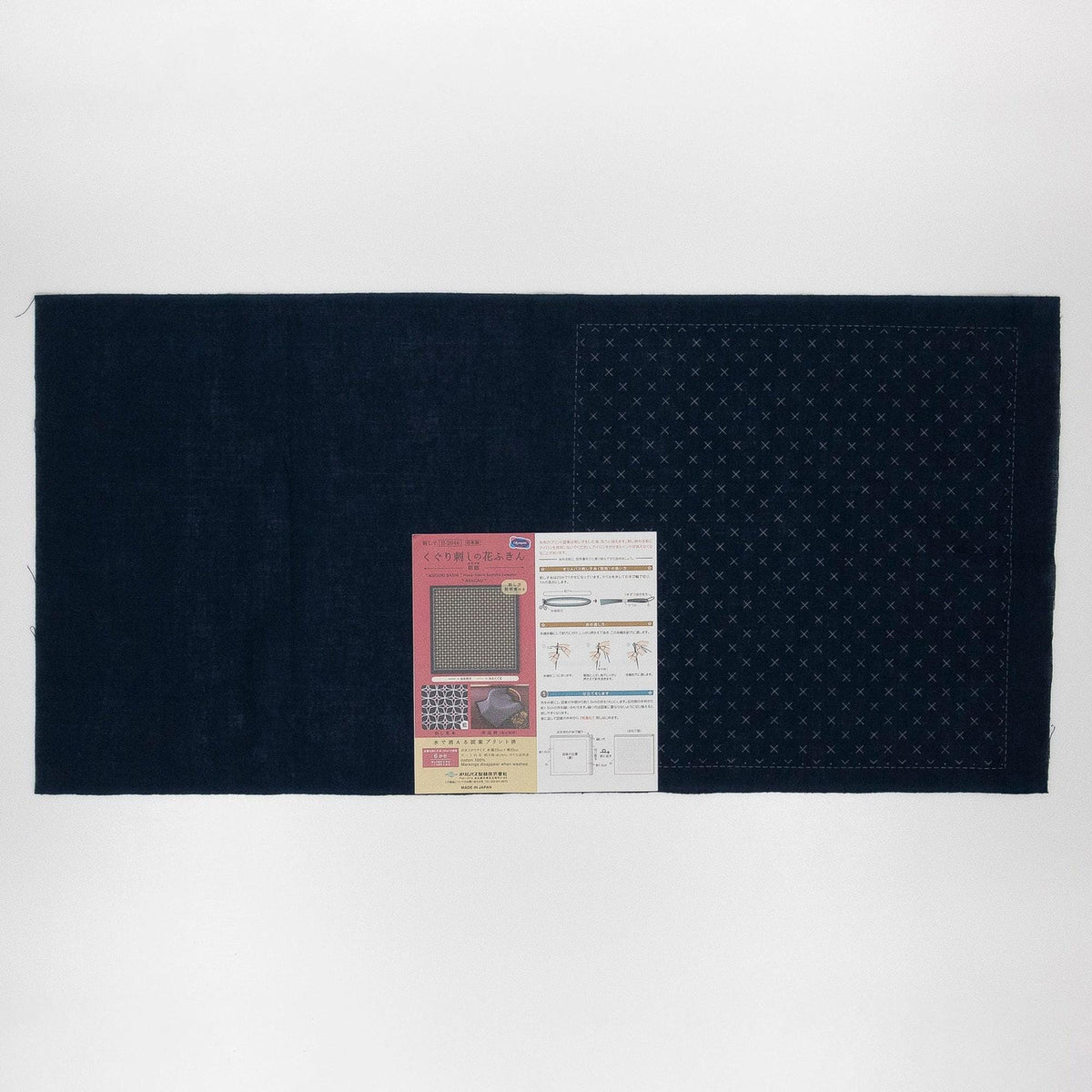 The image is a black fabric with a white pattern on it, and there is a small piece of paper with text and images next to it.