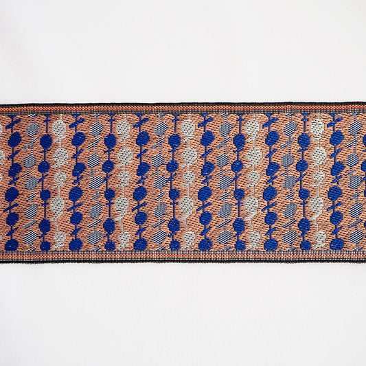 a close-up view of a decorative textile with a repeating pattern of blue and orange circles and lines.