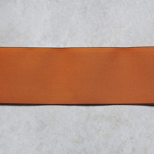 a single, horizontal orange fabric or ribbon placed on a plain, gray surface.
