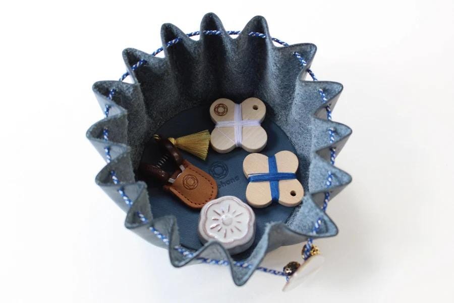 A blue felt basket with a handle, containing various small objects such as a small white object, a brown object, and a blue and white object.