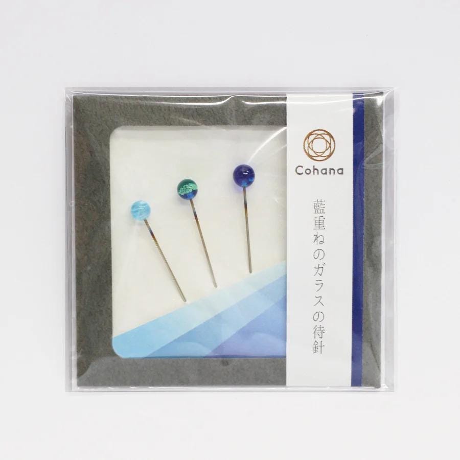 a package containing three colorful pins, each with a unique design, displayed in a clear plastic bag.