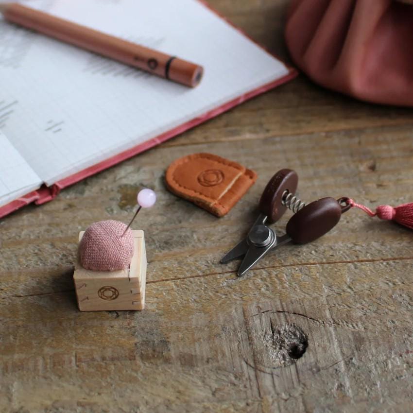 a wooden table topped with a pair of scissors and a ball of yarn