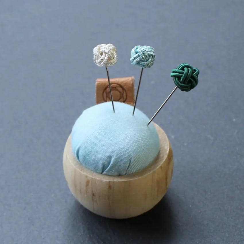 a small wooden holder with three pins in it