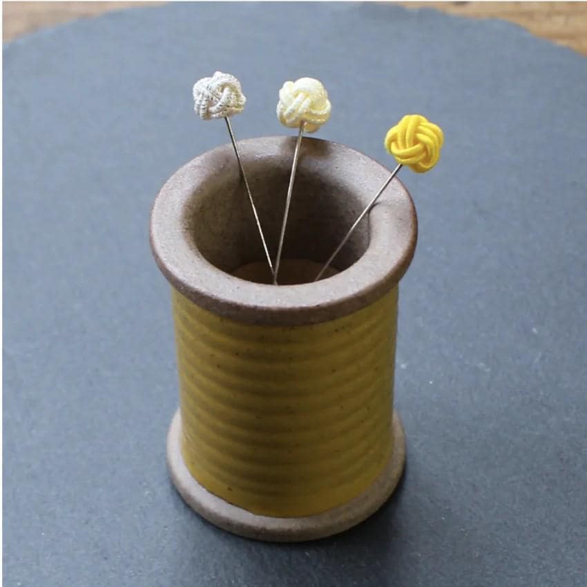 a spool of thread with some yellow and white flowers in it