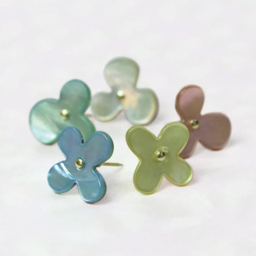 a group of four flower shaped earrings sitting on top of a table