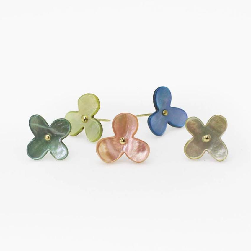 four different colored flower shaped studs on a white background