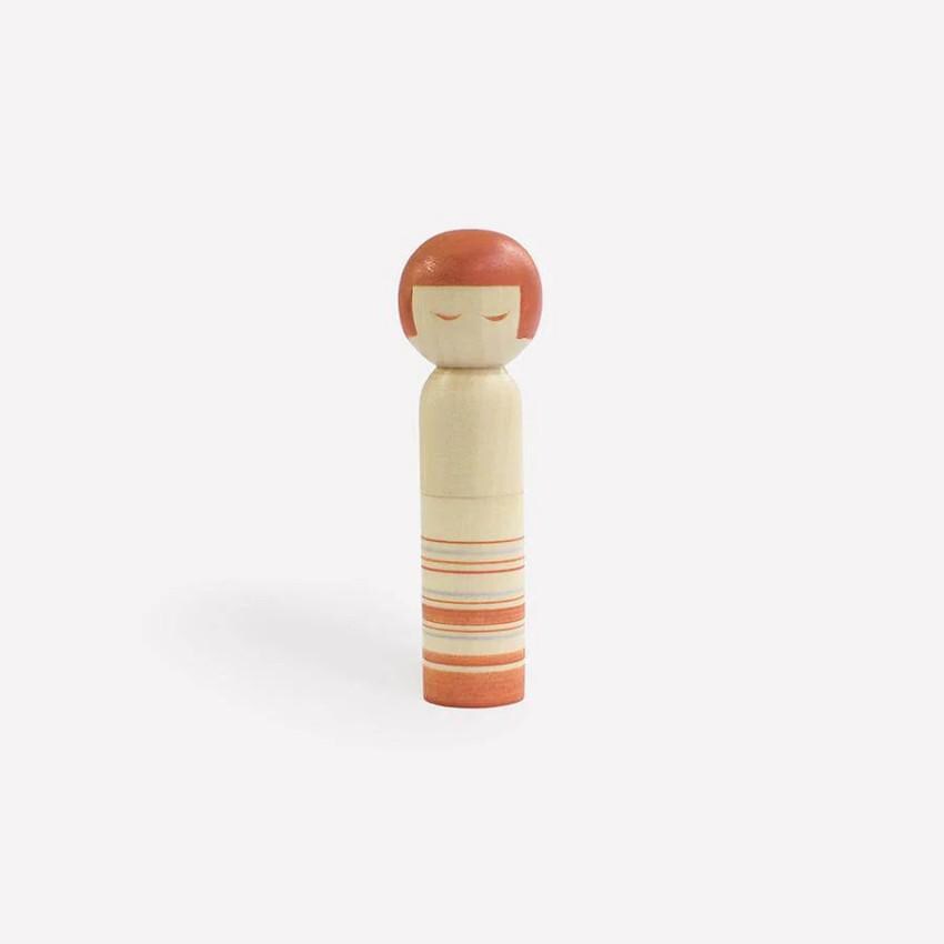 a small wooden doll with a red hair