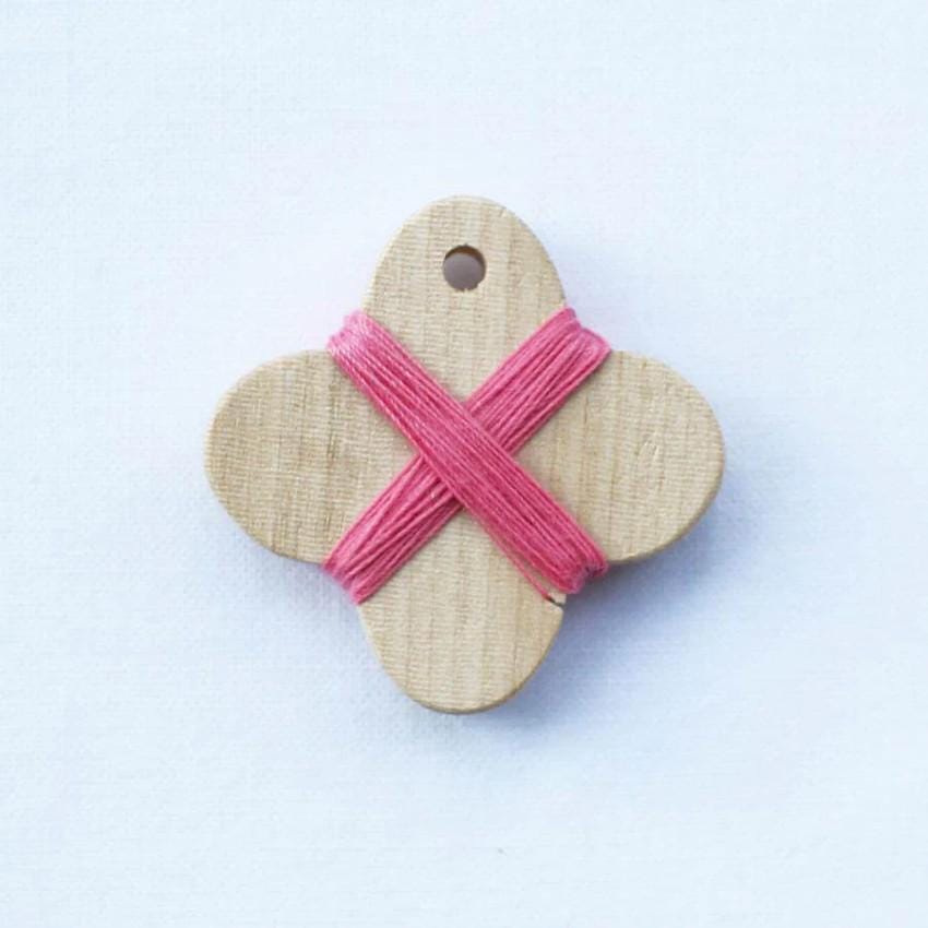 a wooden ornament with a pink ribbon tied around it