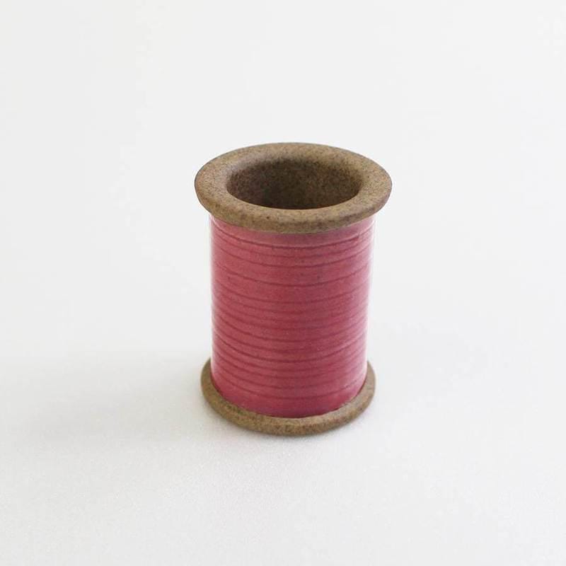 a spool of pink thread on a white surface
