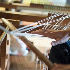 a woman weaving a piece of cloth on a loom