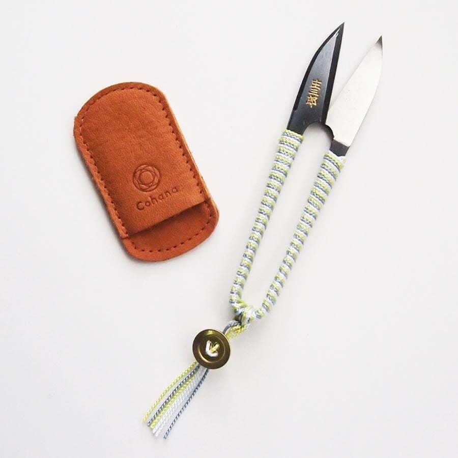 a pair of scissors sitting next to a leather case