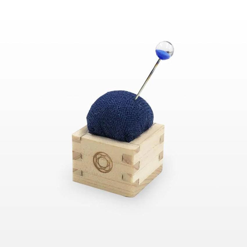 a blue ball of yarn sitting on top of a wooden block