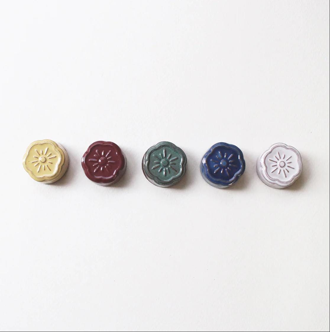 a row of four different colored buttons on a white surface