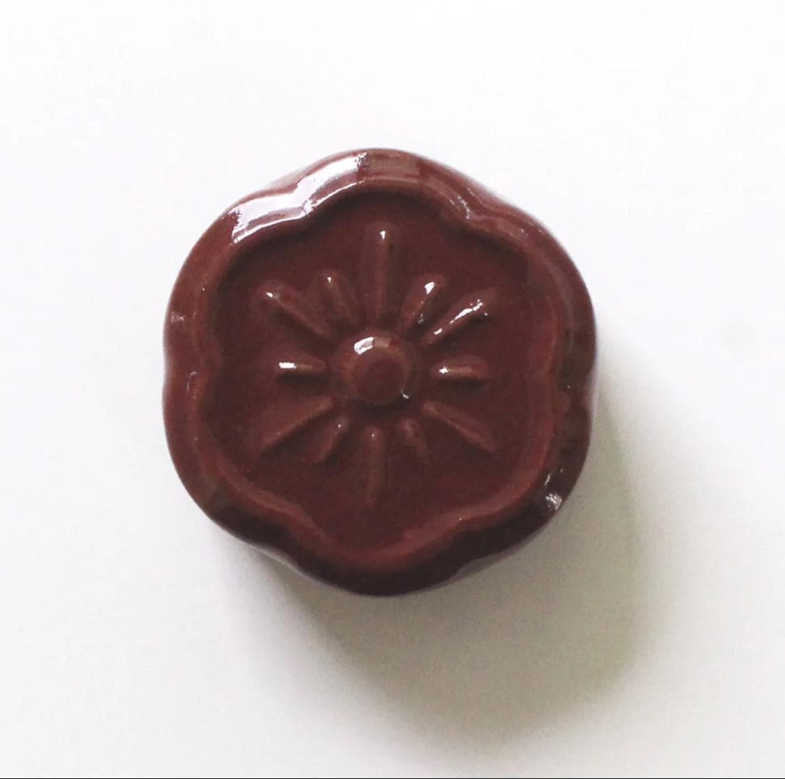 a close up of a wax stamp on a white surface