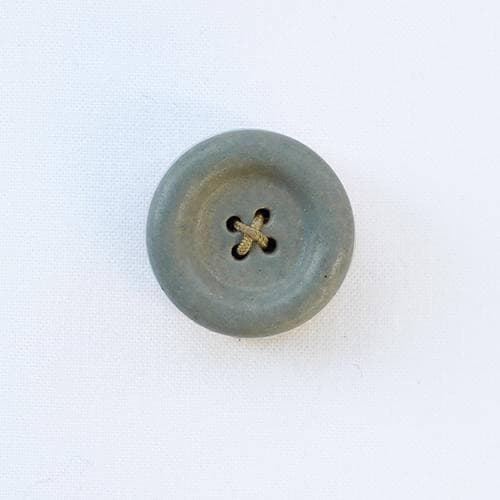 a button with a cross on it sitting on a white surface