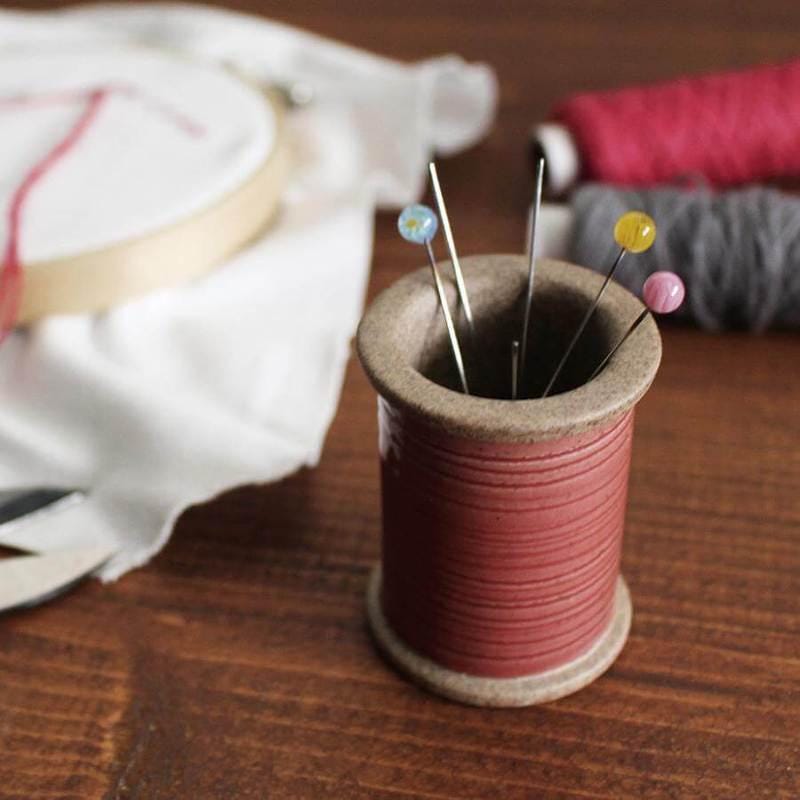a spool of thread sits next to a spool of thread