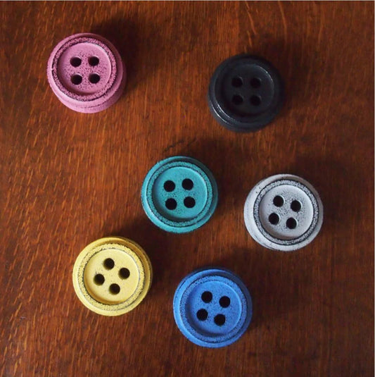 a group of four buttons sitting on top of a wooden table