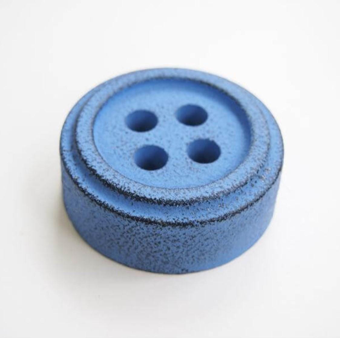a blue button sitting on top of a white table