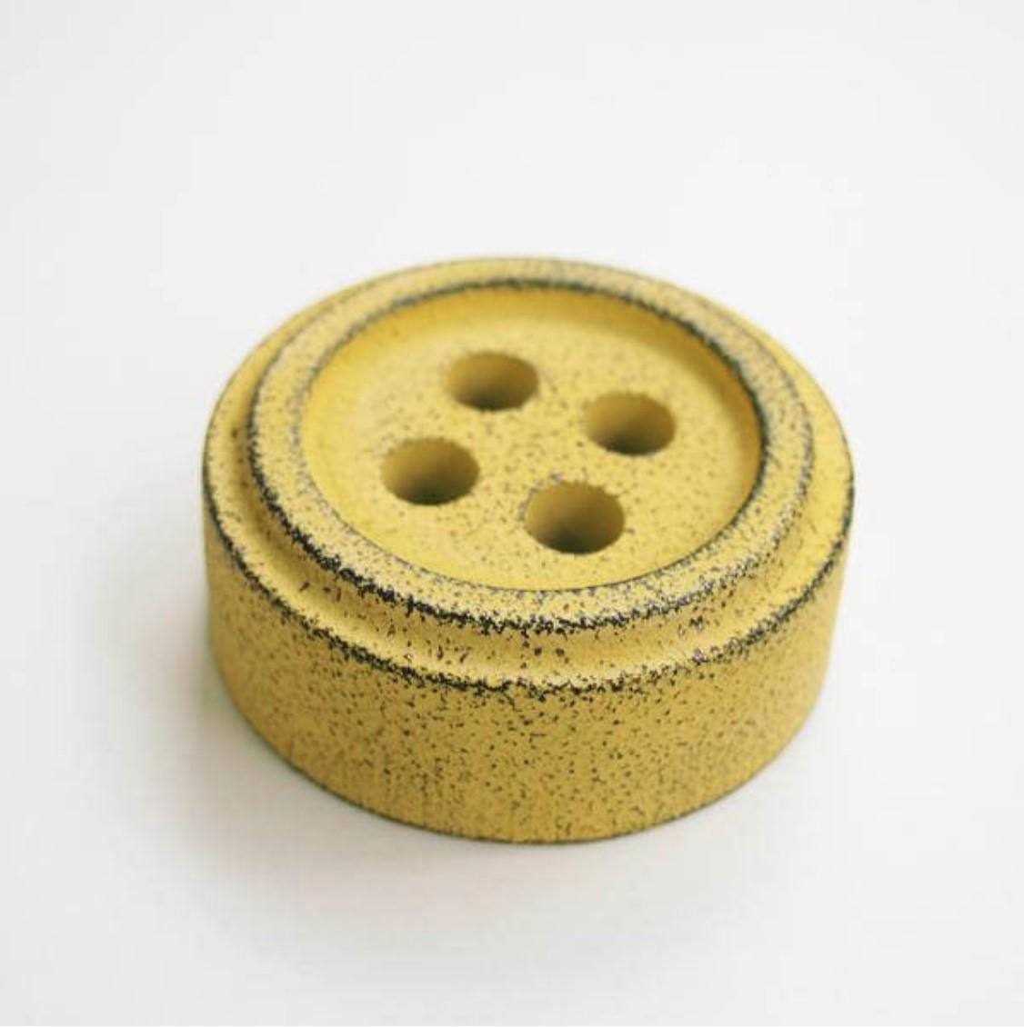 a yellow button on a white surface