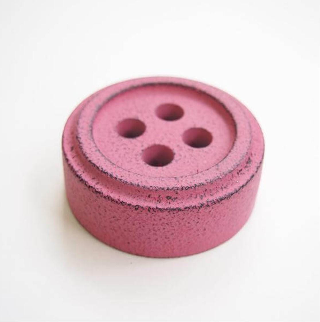a close up of a pink button on a white surface