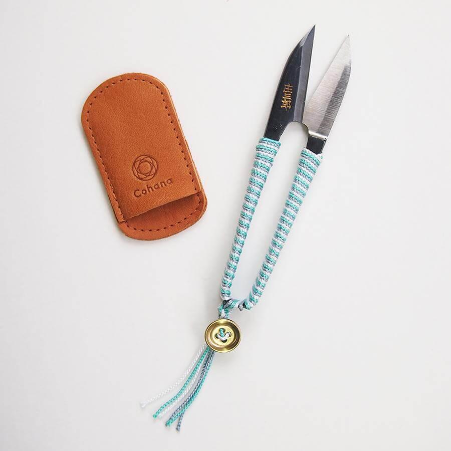 a pair of scissors sitting next to a leather case
