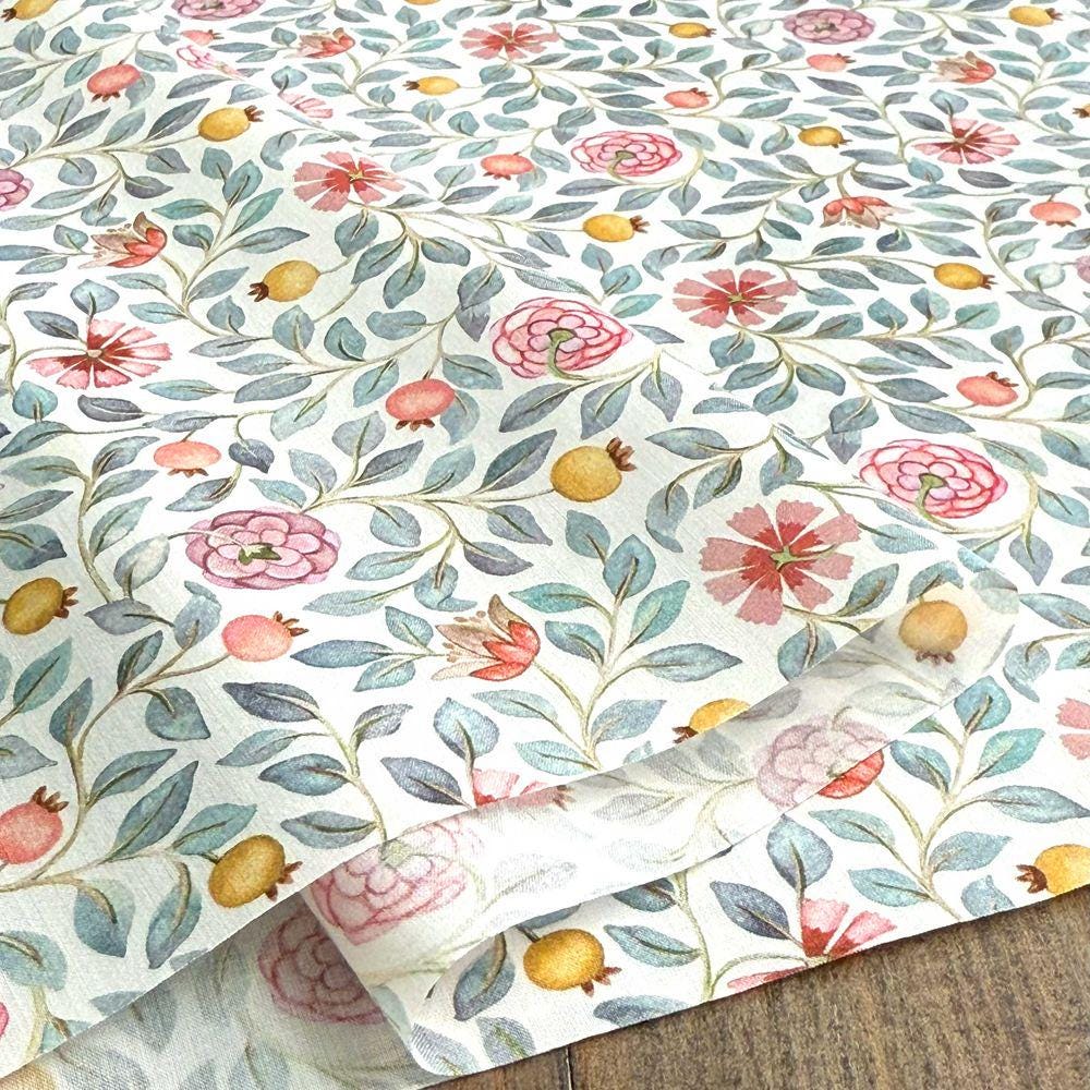 a close-up view of a fabric with a floral pattern. The fabric has a white background with a repeating pattern of pink flowers, green leaves, and yellow fruits. The pattern is intricate and detailed, creating a visually appealing design.