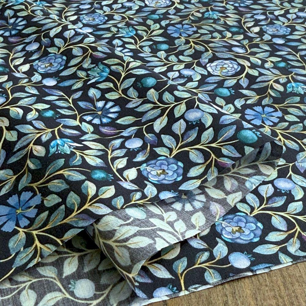 a close-up view of a fabric with a floral pattern in shades of blue and green. The pattern consists of various flowers and leaves, creating a visually appealing and intricate design. The fabric appears to be a piece of cloth or textile, with the floral pattern covering a significant portion of its surface.