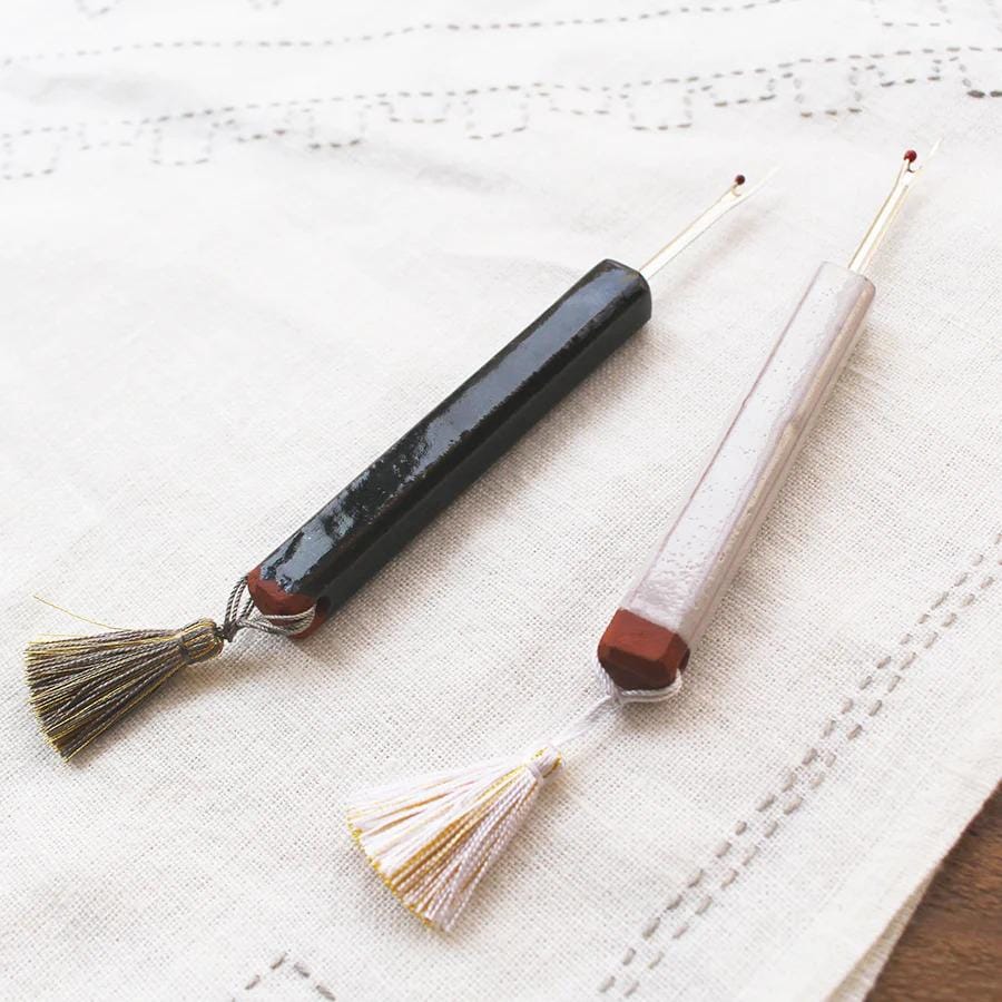 Two crochet hooks with tassels are resting on a white cloth.
