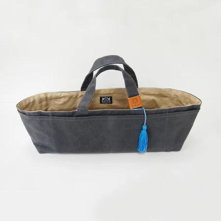 A gray canvas tote bag with a tassel hanging from the handle.