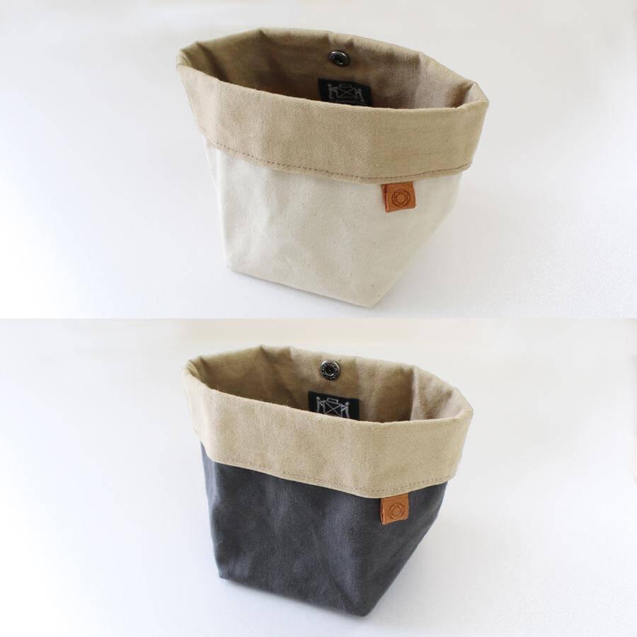 two beige and gray fabric baskets with a button closure, placed on a white background.